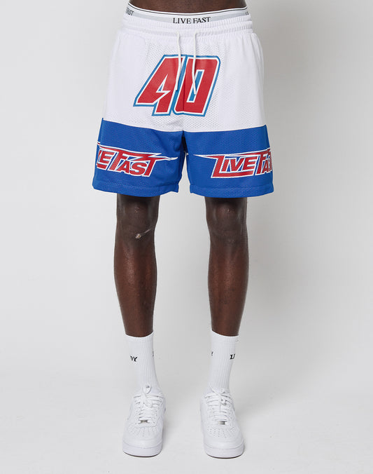 A person models LFDY Racing Mesh Shorts by LIVE FAST DIE YOUNG—regular fit white polyester shorts with a bold red 40, blue LIVE FAST stripes, paired with white socks and sneakers against a plain white background.