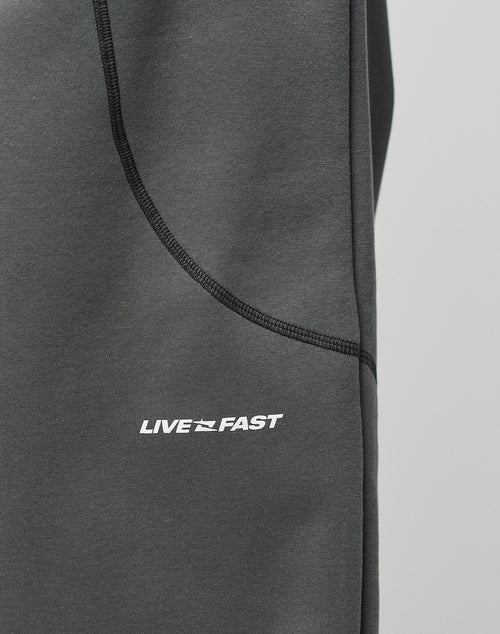 Close-up of the LFDY Active Fleece Jogger by LIVE FAST DIE YOUNG in dark gray, featuring black seams and a logo print with LIVE FAST and a dynamic graphic between the words.
