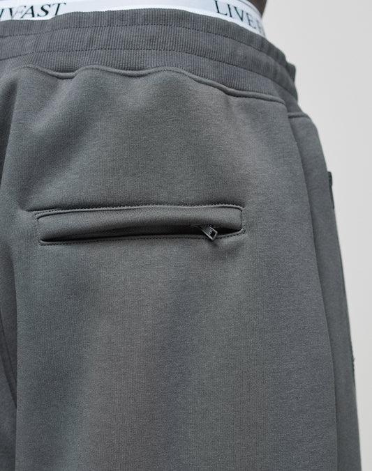 Close-up of the back pocket on LFDY Active Fleece Jogger by LIVE FAST DIE YOUNG, highlighting the zippered pocket and flatlock-topstitching. The waistband of white LIVE FAST DIE YOUNG underwear is partially visible above the pants.