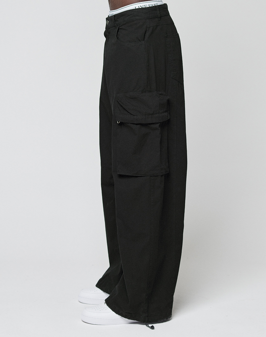 Someone wearing LIVE FAST DIE YOUNG’s LFDY Baggy Cargo pants with großen Cargo-Taschen and Baggy Fit, styled with white sneakers and posing against a plain white background.