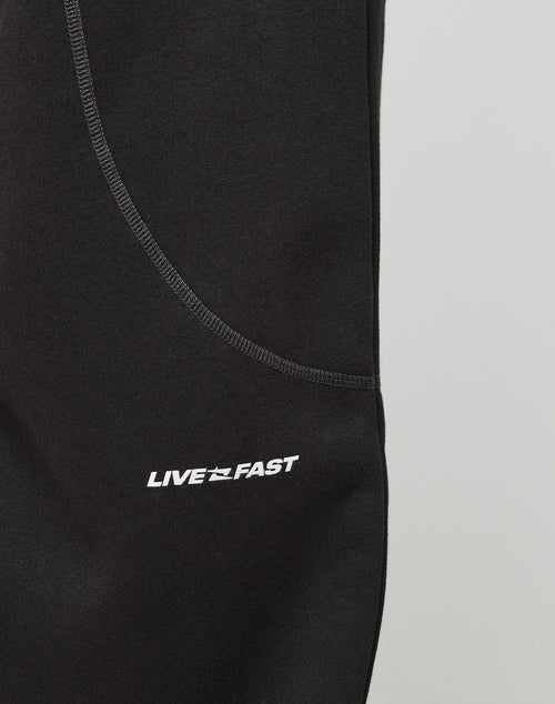 Close-up of the LFDY Active Fleece Jogger by LIVE FAST DIE YOUNG in black wide fit, featuring a visible seam and white LIVE FAST logo print with a star graphic between the words.