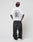 Someone wearing the LIVE FAST DIE YOUNG LFDY Under Fire Tee in oversize white, black jeans, white sneakers, and a purple cap stands with their back to the camera against a plain background.