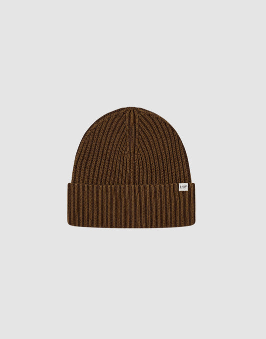 The Washed Rib Knit Beanie by LIVE FAST DIE YOUNG features brown ribbed knit, a folded cuff with a small white tag, made from 100% Baumwolle. One Size for versatile comfort. Displayed on a plain light grey background.