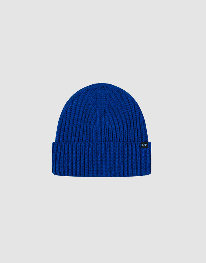 The LIVE FAST DIE YOUNG Rib Knit Beanie in royal blue features a folded brim and is made from soft Polyacryl. Displayed on a plain light grey background. One size fits most for comfortable wear.