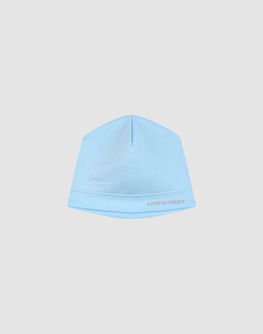 The LIVE FAST DIE YOUNG Performance Beanie is light blue and fitted, with "LIVE FAST" embroidered in white on the front and a reflective logo print, shown against a plain light gray background.