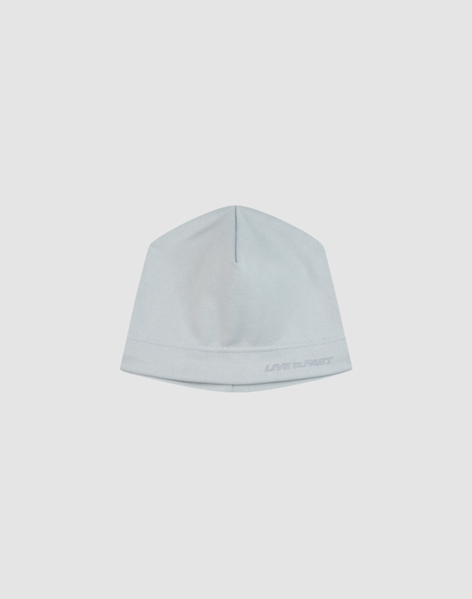 The LIVE FAST DIE YOUNG Performance Beanie is a light blue, fitted hat with subtle stitching, a thin fleece lining for warmth, and a small logo on the lower right edge, shown against a plain white background.