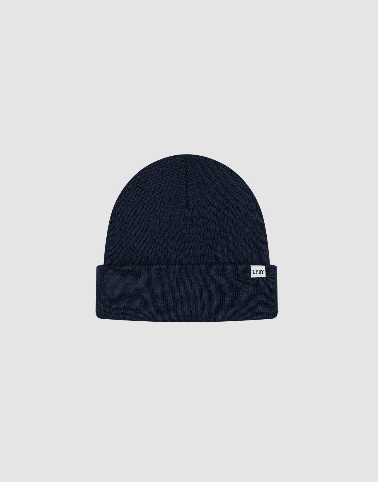 The Basic Beanie by LIVE FAST DIE YOUNG is a plain navy blue, one-size knitted hat with a folded brim and a white LFDT flaglabel on the front, made from soft polyacryl and shown on a light grey background.