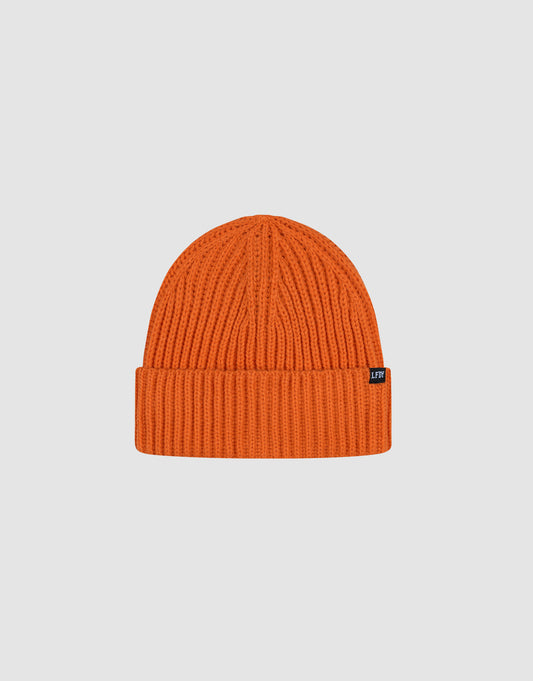 The LIVE FAST DIE YOUNG Rib Knit Beanie in bright orange features a folded cuff, soft polyacryl fabric, and a small black tag on the cuff. Shown against a plain light gray background. One size fits all.