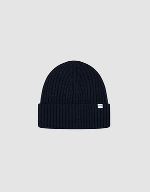 A navy blue LIVE FAST DIE YOUNG Rib Knit Beanie in polyacryl, featuring a folded brim and small white front tag, is displayed on a plain light gray background. This stylish, comfortable beanie comes in one size and offers versatile wear.