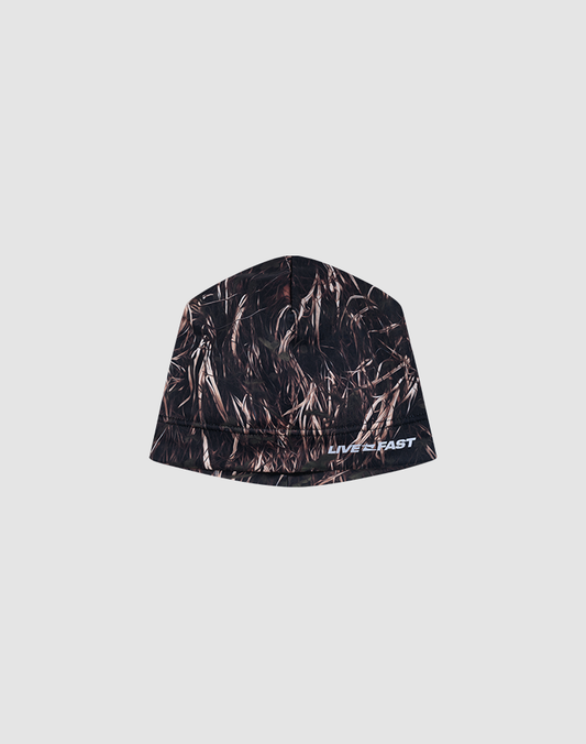The LIVE FAST DIE YOUNG Performance Beanie features a dark brown and black camo polyester design with a white reflective "LIVE FAST" logo on the lower right front, shown against a plain light gray background.