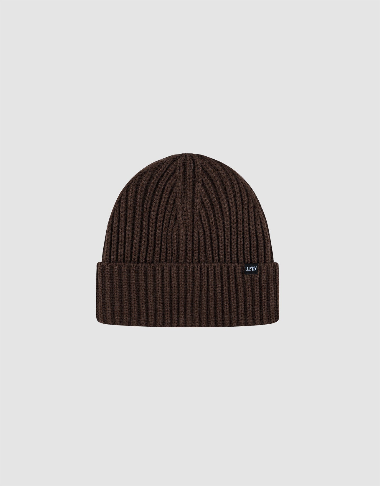 A dark brown Rib Knit Beanie by LIVE FAST DIE YOUNG in polyacryl with a folded cuff, shown on a light gray background. Features a small black tag with white text on the cuff. One Size for versatile wear.