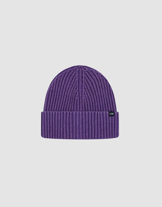 The LIVE FAST DIE YOUNG Washed Rib Knit Beanie in purple is made from 100% cotton, features a folded brim and a small black tag with white text, and comes in one size. Displayed against a plain white background.