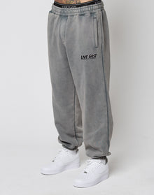 Person wears LFDY Europe Run Jogger by LIVE FAST DIE YOUNG, featuring LIVE FAST text on the left thigh, elastic cuffs, and a matching waistband. Styled with white Nike sneakers against a plain white background highlighting the loose fit. | model