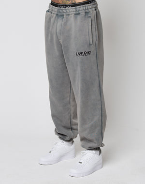 Person wears LFDY Europe Run Jogger by LIVE FAST DIE YOUNG, featuring LIVE FAST text on the left thigh, elastic cuffs, and a matching waistband. Styled with white Nike sneakers against a plain white background highlighting the loose fit.