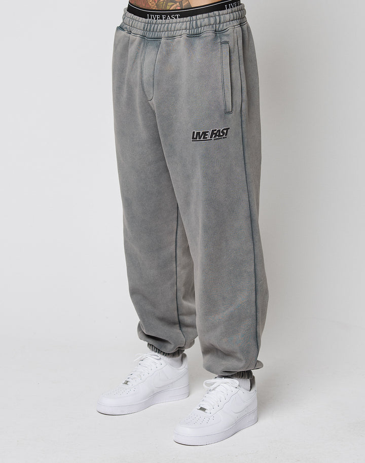 Person wears LFDY Europe Run Jogger by LIVE FAST DIE YOUNG, featuring LIVE FAST text on the left thigh, elastic cuffs, and a matching waistband. Styled with white Nike sneakers against a plain white background highlighting the loose fit. | model