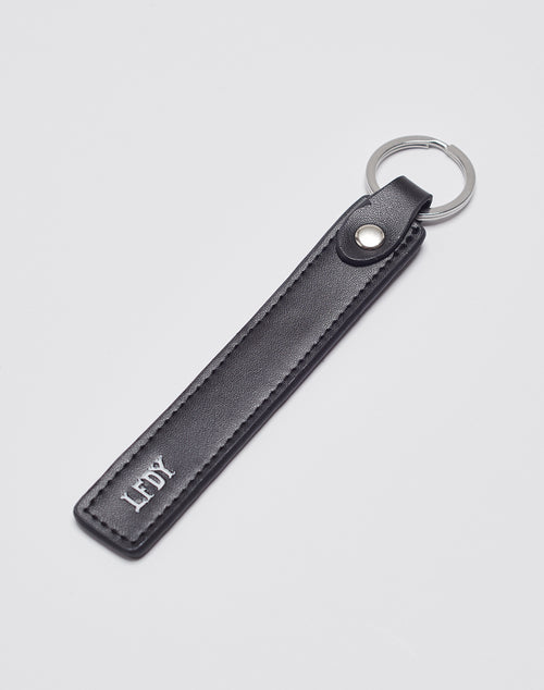 The Basic Keychain by LIVE FAST DIE YOUNG features black PU leather with a stitched border, an Edelstahl ring, and LFDY printed in white near the bottom. The product is shown against a plain light gray background.