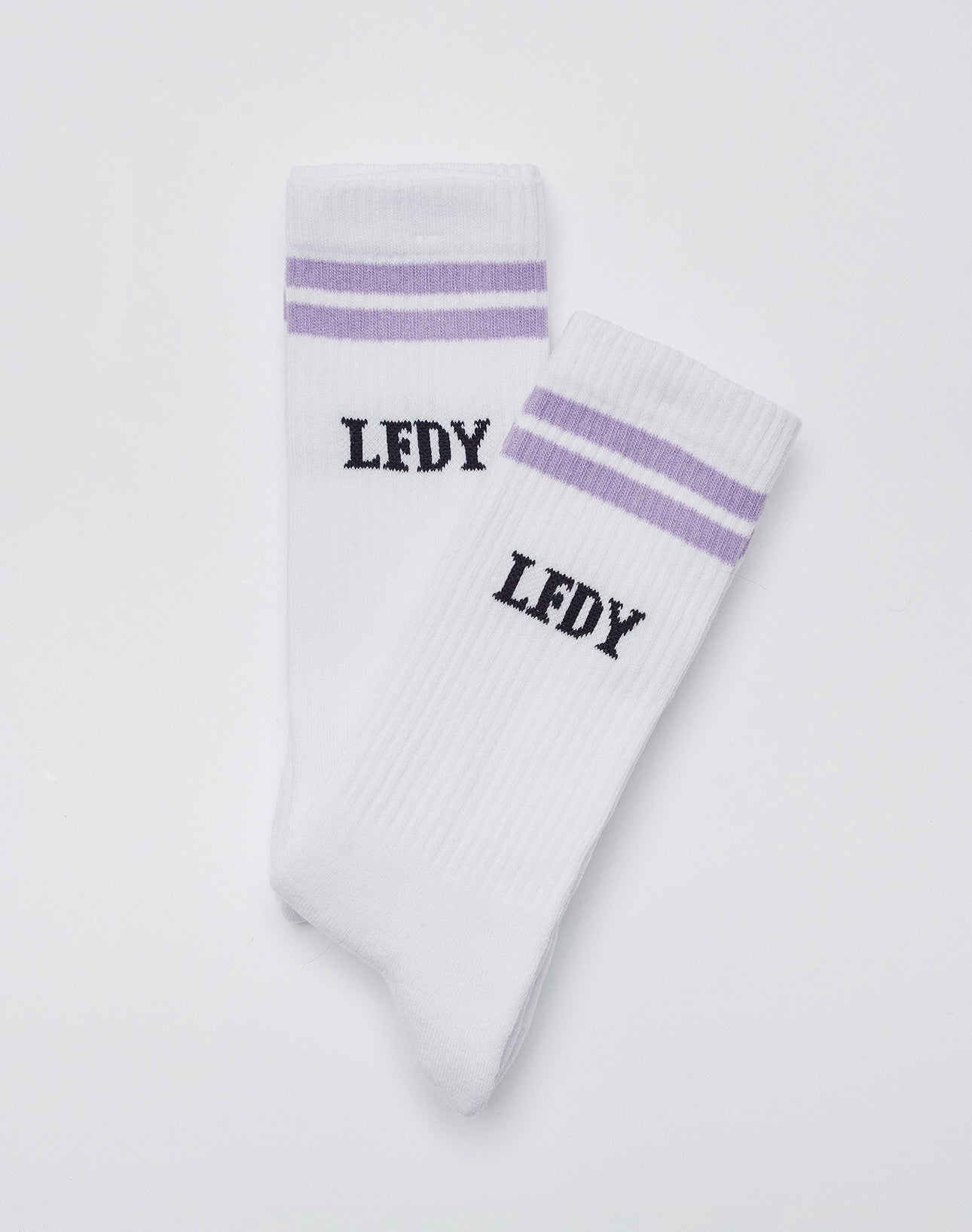 A pair of white LIVE FAST DIE YOUNG Basic Socks (2 Pack) with two purple stripes near the top, black “LFDY” text beneath the stripes, and a hint of elastane for comfort, displayed on a plain white background.