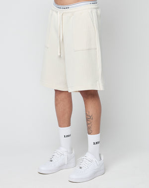 A person wears LIVE FAST DIE YOUNG Basic Knit Shorts with an elastic waistband, white LFDY socks, and white Nike sneakers, standing against a plain light background. Only the lower body and legs are visible.