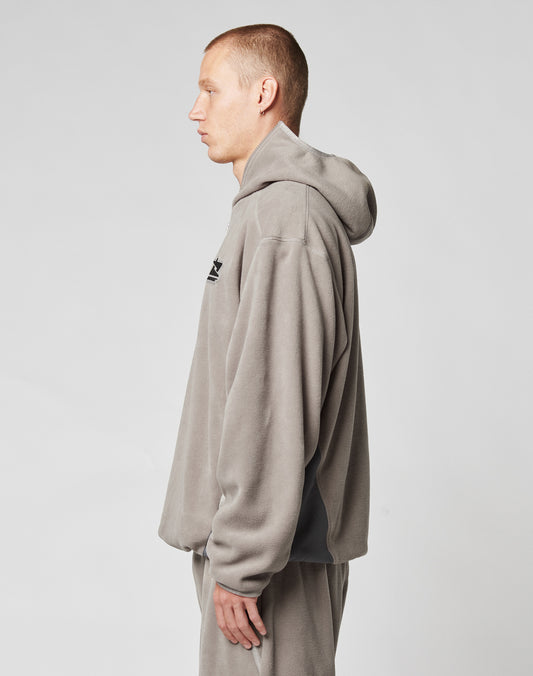 A person with short hair stands in profile, facing left, wearing the LIVE FAST DIE YOUNG Live Fast Fleece Halfzip in light gray with matching sweatpants against a plain light background.