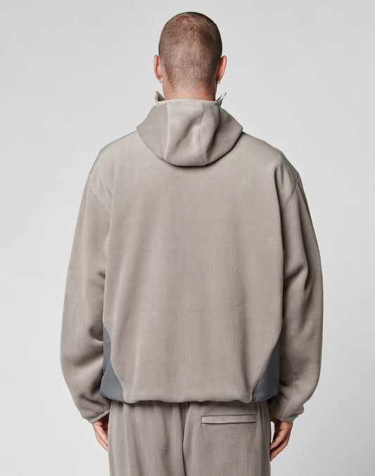A person is seen from behind wearing the LIVE FAST DIE YOUNG Live Fast Fleece Halfzip in light gray with matching pants. The oversize fit jacket features a subtle nylon einsatz detail, hood up, head shaved, set against a plain background.