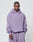 A man faces forward in a loose, lavender LIVE FAST DIE YOUNG Basic 360 Hooded and matching sweatpants, both in Oversize Fit. The hoodie includes a front pocket, left chest text, and soft Baumwolle-Polyester blend. Plain, light background.