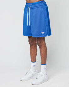 A person wears blue Basic Mesh Shorts by LIVE FAST DIE YOUNG with an elastic waistband and drawstring featuring LIVE FAST, paired with white socks with blue trim and white sneakers, standing against a plain white background.