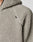 Close-up of a light gray, textured sherpa fleece Live Fast Teddy Jacket by LIVE FAST DIE YOUNG. Features a black shoulder tag, partially visible zipper, hood, and stylish nylon accents.