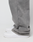 A close-up side view of a person wearing the LIVE FAST DIE YOUNG Basic Wide Jogger in gray, featuring an oversized fit that drapes over white sneakers, set against a plain white background.
