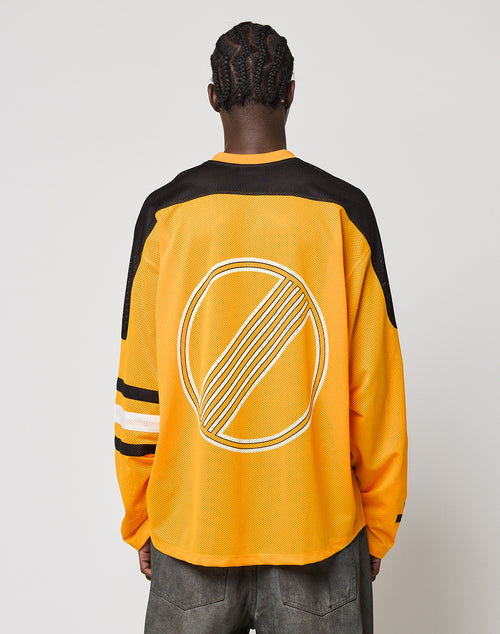 A person faces away, wearing an oversize fit LFDY Autobahn Jersey by LIVE FAST DIE YOUNG. The yellow and black polyester jersey features white sleeve stripes and a large circular multilogo emblem on the back. The background is plain white.