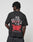 A person with short, twisted hair wears the LFDY We Walked Tee by LIVE FAST DIE YOUNG: an oversized black 100% cotton T-shirt with bold white and red WE WALKED SO THEY CAN RUN front/back prints, flame graphics, and BE YOUNG FOREVER at the bottom.