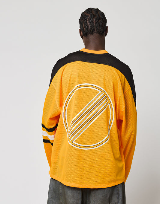 A person with braided hair is seen from behind, wearing an oversize fit yellow and black LFDY Autobahn Jersey by LIVE FAST DIE YOUNG, featuring white sleeve stripes and a large circular multilogo design on the back. The background is plain white.