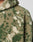 Close-up of a person wearing the LIVE FAST DIE YOUNG Live Fast Teddy Jacket in green and beige with fuzzy, camouflage-like sherpa fleece and embossed branding. Visible: upper chest, shoulder, and partial hood with visor opening.