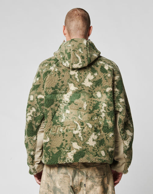 A person with short hair is shown from behind, wearing the LIVE FAST DIE YOUNG Live Fast Teddy Jacket in a camouflage pattern with Raglan sleeves and hood, paired with matching pants, set against a plain light background.