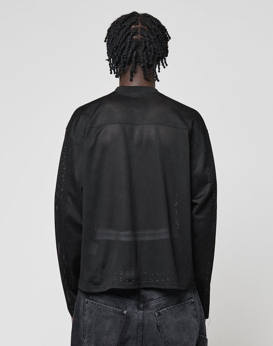 A person with short, twisted braids is seen from behind wearing the LFDY Flash Jersey by LIVE FAST DIE YOUNG—an oversize-fit, long-sleeve black mesh top—paired with faded black jeans against a plain light gray background.