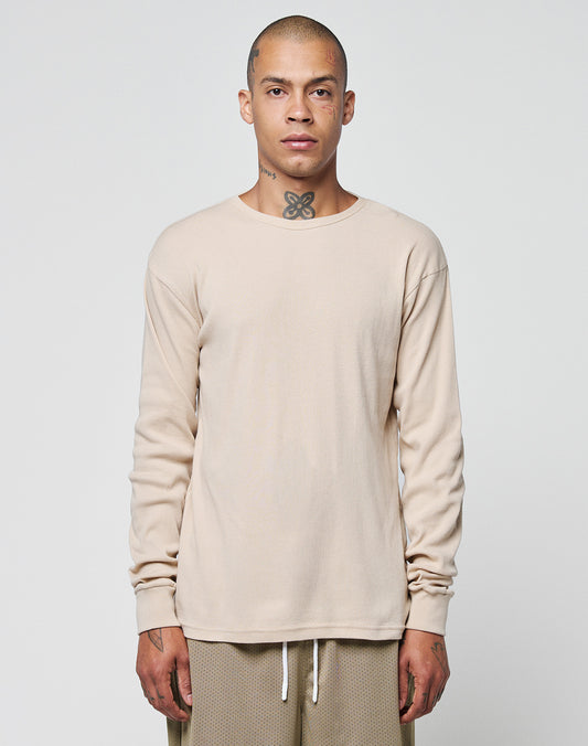 A person with a shaved head and neck tattoo stands facing forward, wearing the LIVE FAST DIE YOUNG Basic Regular Rib Longsleeve in beige and beige textured pants with white drawstrings, Regular Fit, against a plain light background.