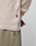 A close-up of a person wearing the LIVE FAST DIE YOUNG Basic Regular Rib Longsleeve in beige, featuring Ripp-Bündchen and a small black tag, paired with light olive green Regular Fit perforated pants. The person's hands are partially behind their back.
