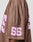 A side view of a person wearing the LIVE FAST DIE YOUNG LFDY Mesh Jersey, an oversized brown sports top featuring large pink number 55 on the sleeve and back.