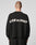 A person with short hair is seen from behind wearing the LIVE FAST DIE YOUNG Live Fast Boucle Sweater in black, featuring a white LIVE FAST slogan on the back, an oversize fit, and set against a plain light background.