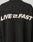 The LIVE FAST DIE YOUNG Live Fast Boucle Sweater is a black oversized polyester sweater with bold white LIVE FAST text—lightning bolt as the I—on the back, designed for all-day comfort.