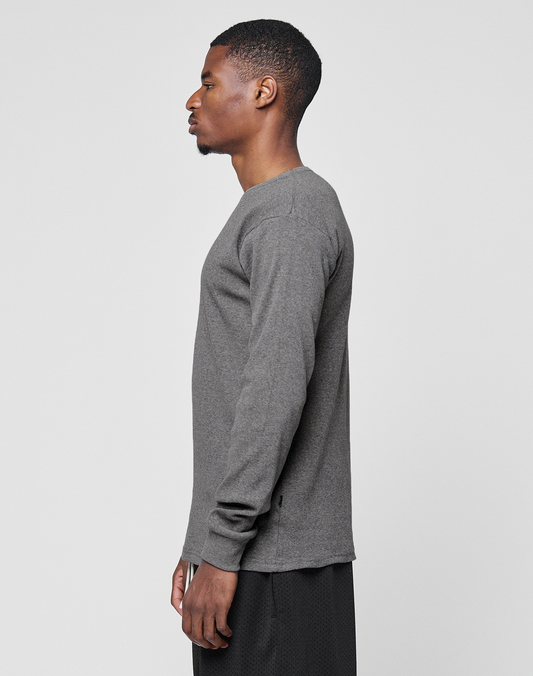 A man stands in profile facing left, wearing the LIVE FAST DIE YOUNG Basic Regular Rib Longsleeve and black shorts against a plain light gray background.