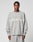 A person wears the LIVE FAST DIE YOUNG Live Fast Boucle Sweater in an oversized light gray fit with matching pants. The 100% polyester sweater displays blurred white LIVE FAST text across the chest. The background is plain and light-colored.