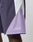 A close-up of a person wearing LIVE FAST DIE YOUNG Basic Nylon Trackshorts in a regular fit, color-blocked in purple, lavender, and white. Live Fast is embroidered on the lavender panel. Comfort is ensured by an elastic waistband; background is plain light.