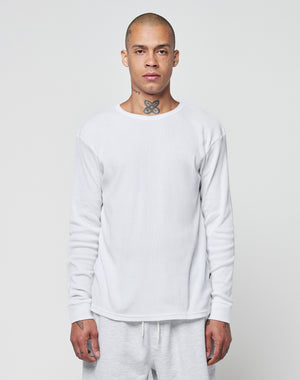 A person with a shaved head and neck tattoo wears the LIVE FAST DIE YOUNG Basic Regular Rib Longsleeve, a plain white shirt, along with matching white pants, standing against a light gray background and facing forward neutrally.