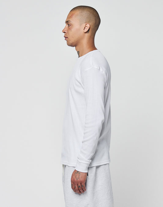 A person with a shaved head and visible tattoos stands in profile against a white background, wearing the LIVE FAST DIE YOUNG Basic Regular Rib Longsleeve in Regular Fit and light-colored pants, both made from soft Baumwolle for comfort.