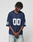 A person wearing the oversized navy blue LFDY Mesh Jersey by LIVE FAST DIE YOUNG, featuring a V-Ausschnitt and number 00 on the front and sleeves, stands with hands clasped, looking down against a plain light gray background.