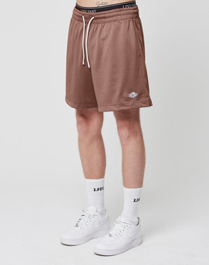 A person in LIVE FAST DIE YOUNG Basic Mesh Shorts with a logo patch and white drawstring, white socks with LFDY text, and white sneakers stands against a plain white background.