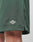 Close-up of the lower part of green Basic Mesh Shorts by LIVE FAST DIE YOUNG, featuring an elastic waistband and a small embroidered LIVE FAST logo patch. Made from polyester mesh and shown worn by someone with light skin.