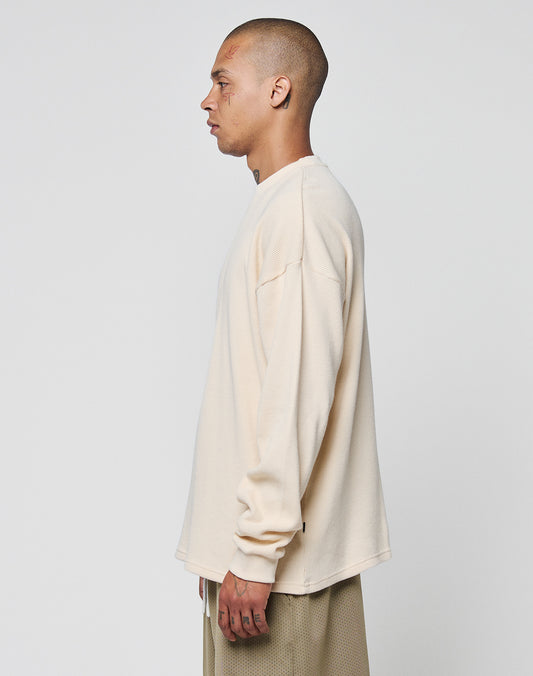 A person with a shaved head, wearing the LIVE FAST DIE YOUNG Blank Waffle Longsleeve and matching beige 100% Baumwolle pants, stands in profile against a plain white background.