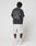 A person faces away, wearing the LIVE FAST DIE YOUNG LFDY Praying Tee with white Liv Fast Forever, Luck Die Young front and back print, light gray shorts, white socks, and white sneakers against a plain background.