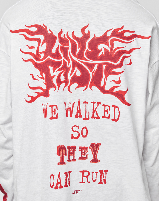 The LFDY We Walked Longsleeve by LIVE FAST DIE YOUNG is a white cotton shirt with an oversize fit, bold red flame-style logo on the front, and “WE WALKED SO THEY CAN RUN” in distressed lettering, plus LFDY initials at the hem.